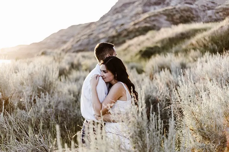 Mann und Frau auf dem Feld umarmen Während der Tageszeit