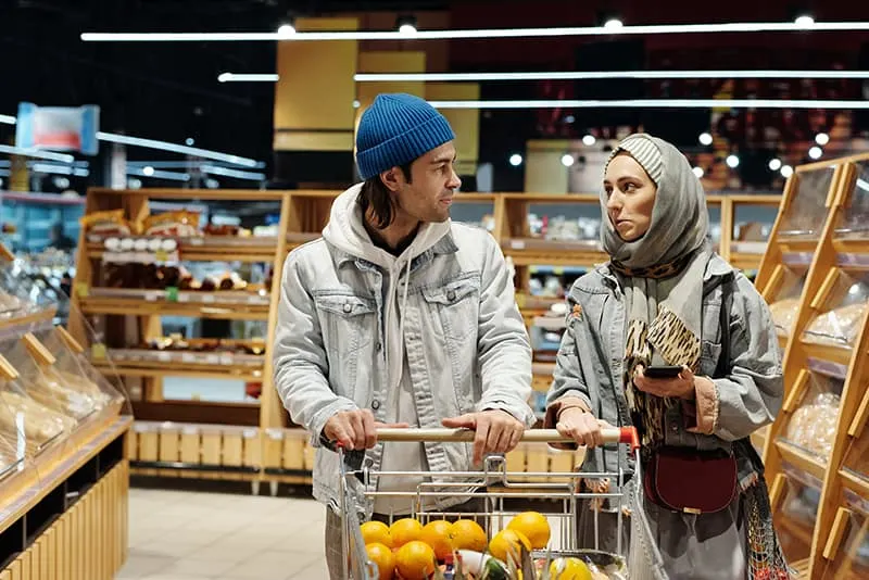 Mann und Frau zusammen im Lebensmitteleinkauf, der neben Regalen steht