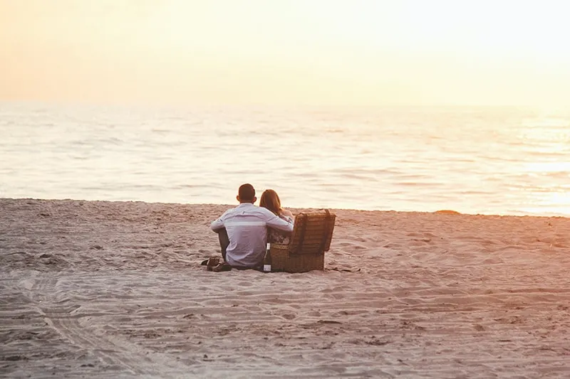 Paar auf einem Picknick am Wasser beobachten Sonnenuntergang