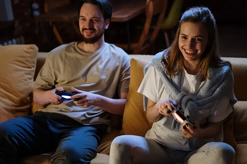 Paar, das zusammen ein Videospiel spielt, während es auf der Couch sitzt