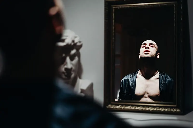 ein narzisstischer Mann, der vor dem Spiegel steht