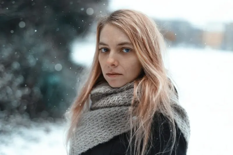 blonde Frau im Schnee mit einem Schal