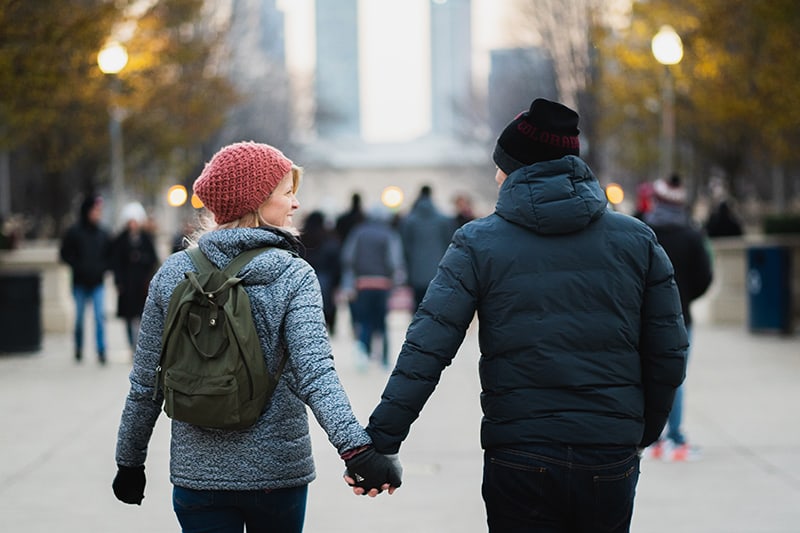 Ein Mann und eine Frau halten sich beim Gehen auf der Promenade an den Händen