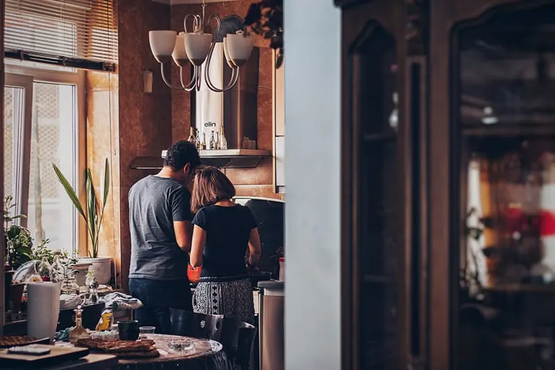 Ein liebevolles Paar, das in einer neuen Wohnung neben dem Herd Essen zubereitet