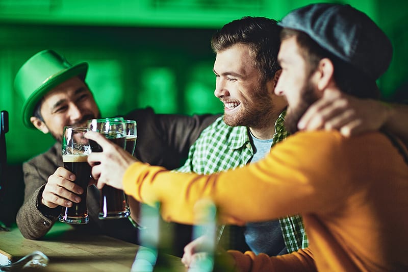 ein lächelnder Mann, der mit Freunden in der Kneipe etwas trinkt