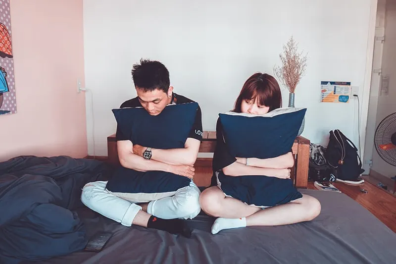 Ein Paar sitzt auf dem Bett und umarmt die Kissen