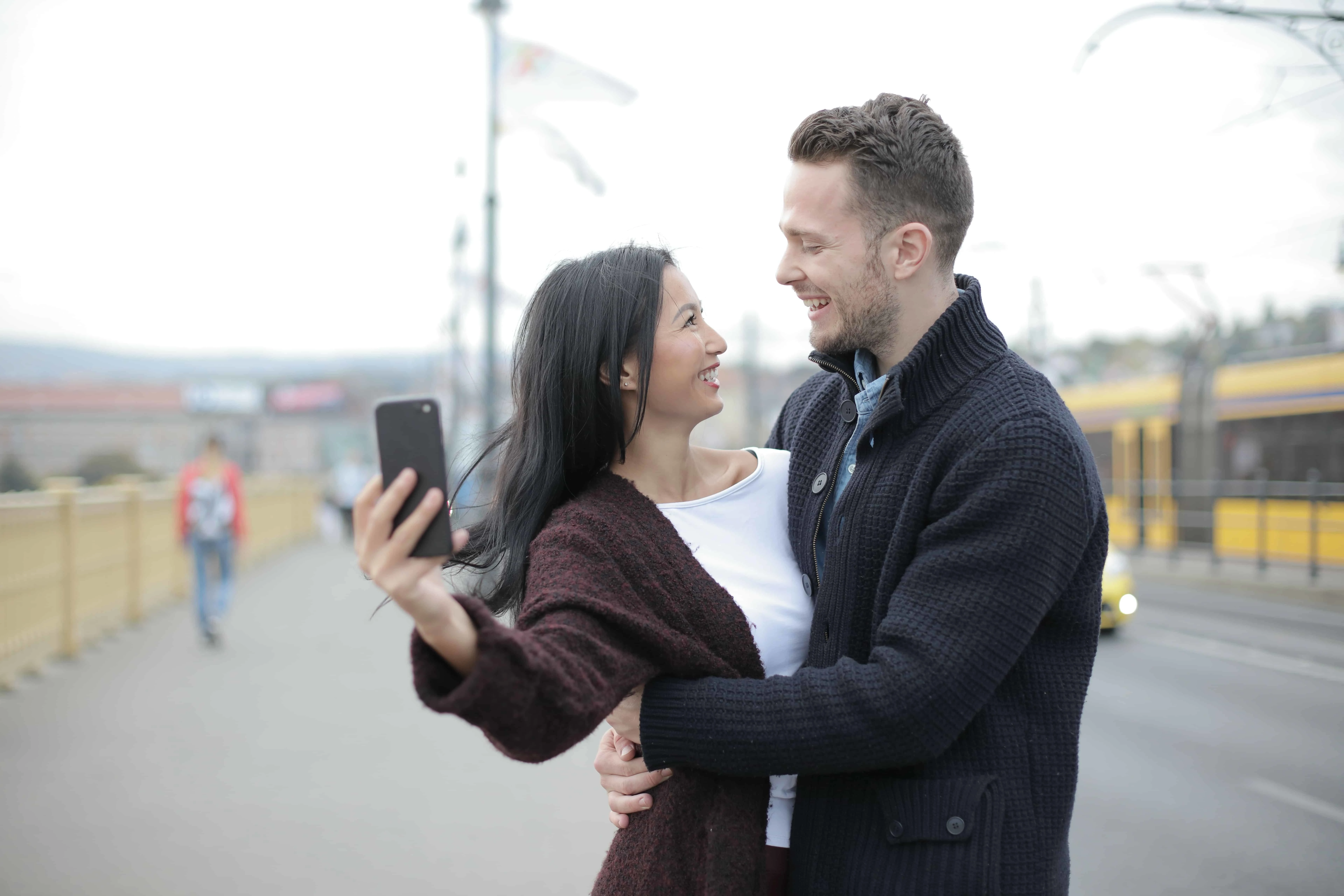 Ein positives Paar macht ein Selfie, während es auf dem Bürgersteig steht