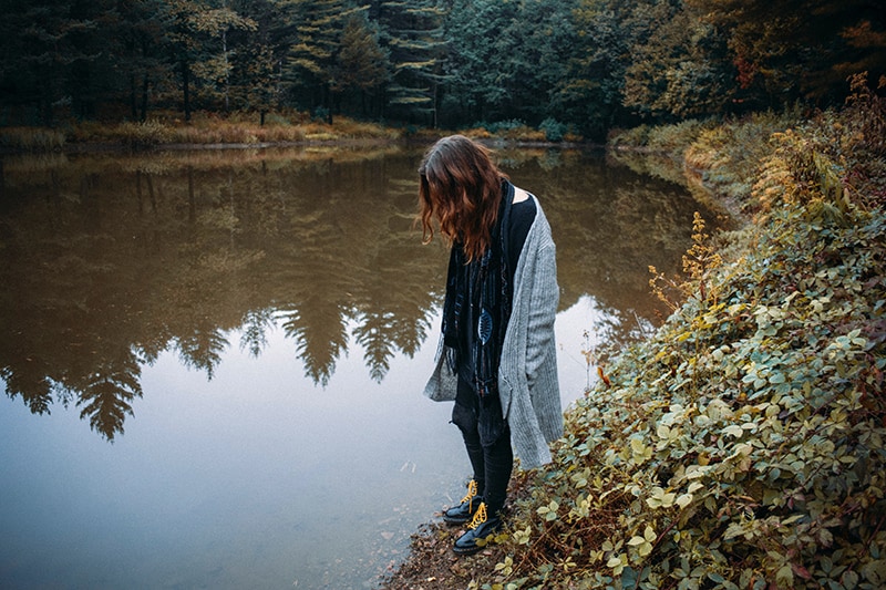 eine Frau, die allein in der Nähe des Flusses steht und hineinschaut