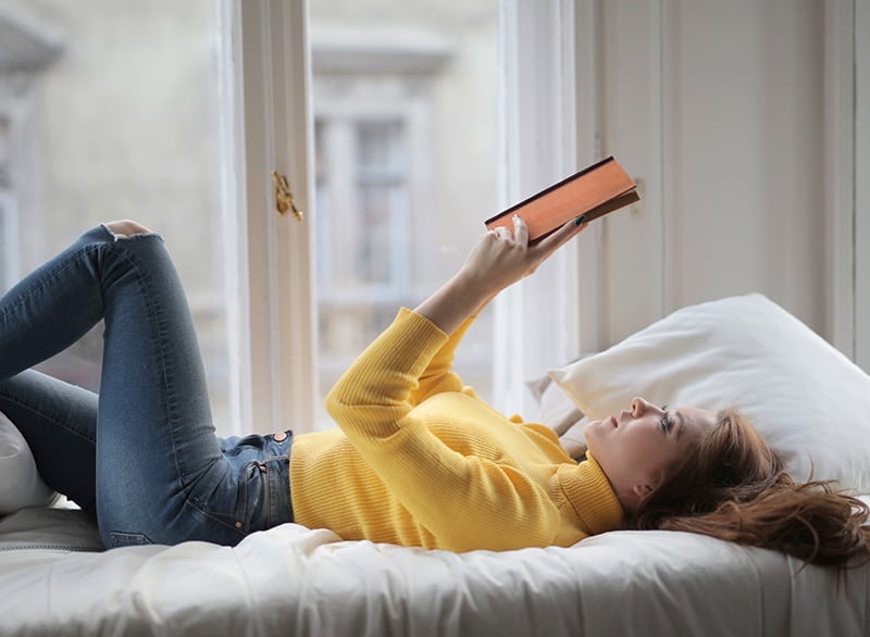 eine Frau, die ein Buch auf dem Bett liest