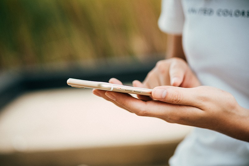 eine Frau, die ein Smartphone in der Hand hält, während sie einen Kontakt löscht