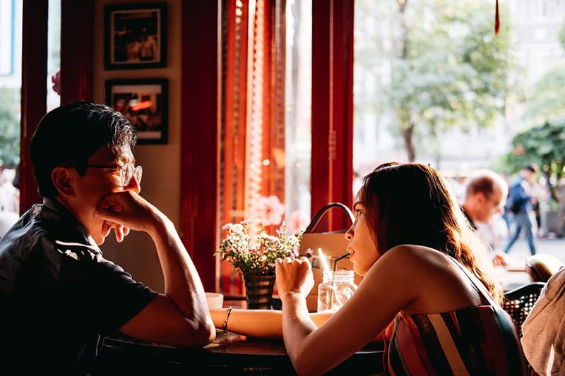 eine Frau, die einen Mann mit einem Problem unterstützt, während sie in der Bar sitzt