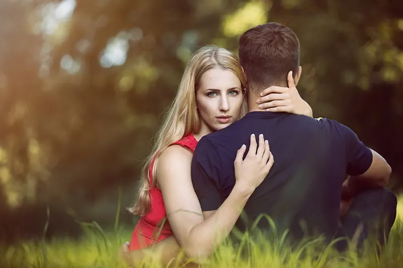 eine Frau, die einen Mann umarmt, während sie im Gras sitzen