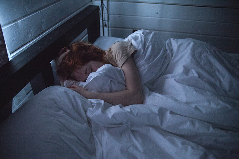 eine Frau, die mit weißen Laken im Bett schläft