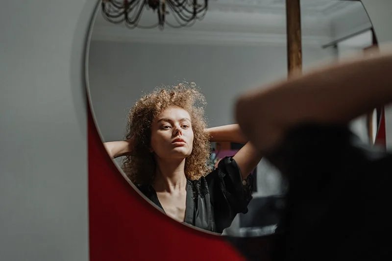 eine Frau, die vor dem Spiegel steht und sich selbst ansieht