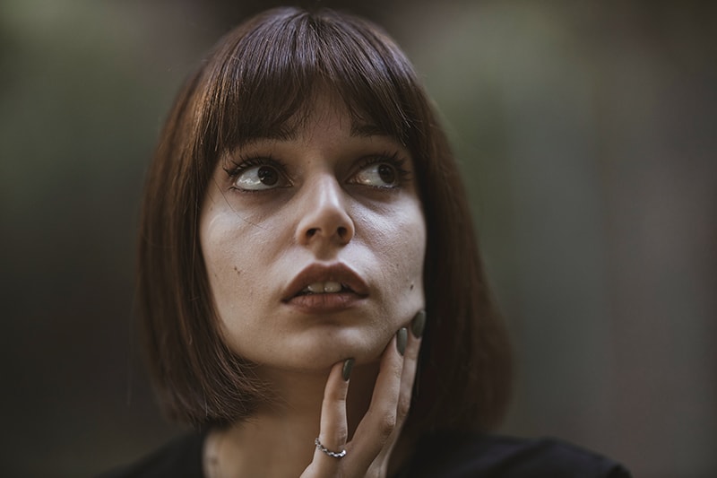 eine Frau mit einem müden Gesichtsausdruck, der das Kinn mit der Hand berührt