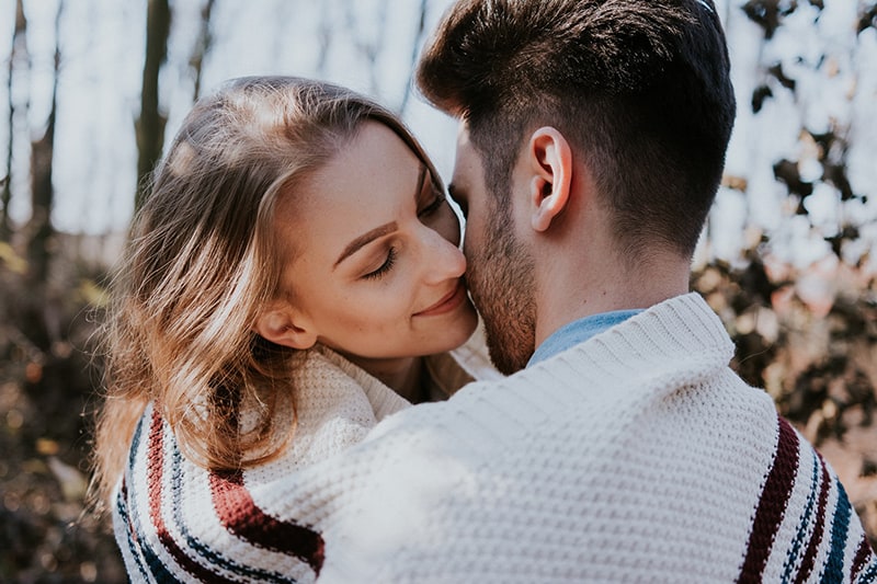 eine Frau und ein Mann, die sich küssen wollen, bedeckt mit einer Decke, während sie draußen stehen