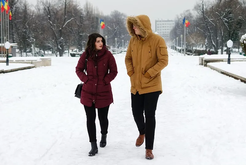 eine Frau und ein Mann reden beim spazierengehen auf dem schnee