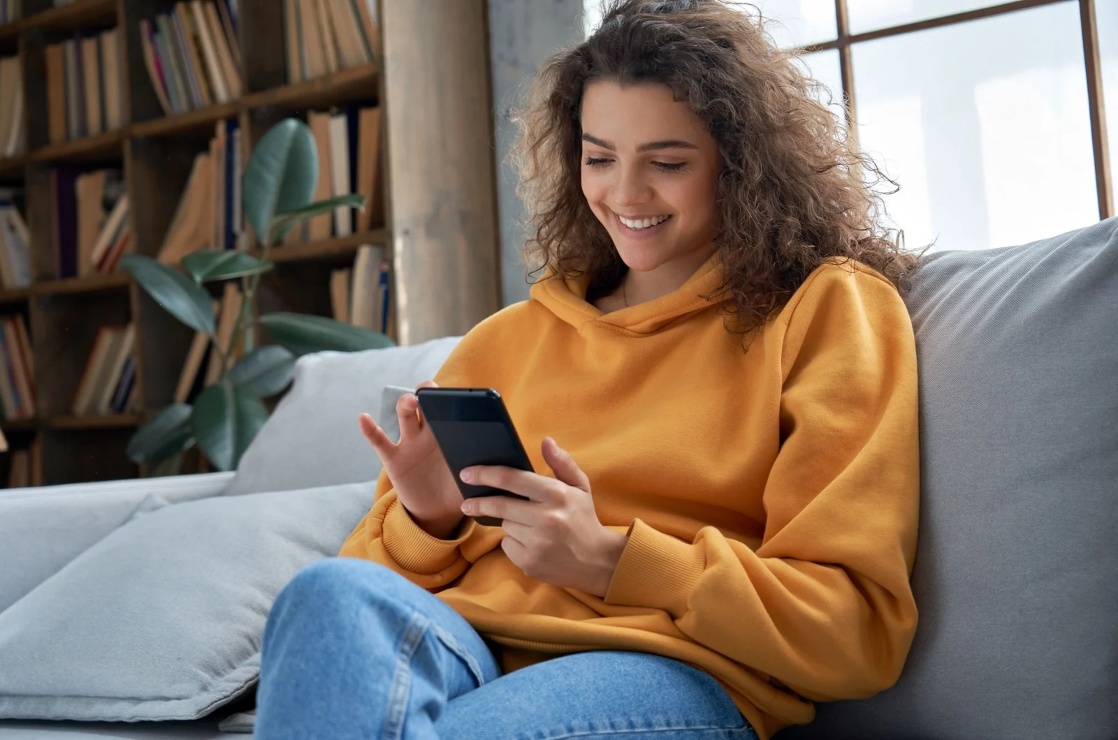 glueckliche Frau, die ein Telefon haelt