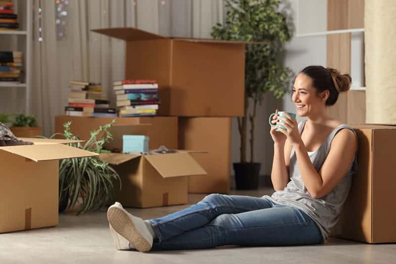 lächelnde Frau, die zu Hause auf dem Boden sitzt