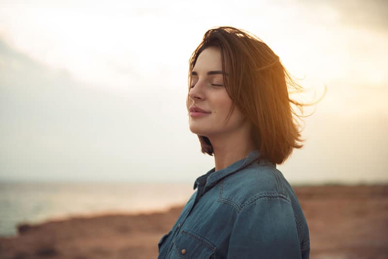 lächelndes Mädchen, das am Meer steht