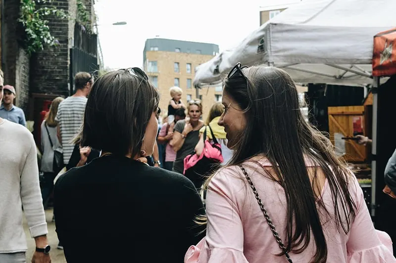 zwei Frauen gehen zusammen über den Straßenmarkt