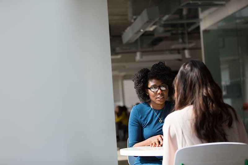 Zwei Frauen sprechen über Probleme, während sie am Tisch sitzen