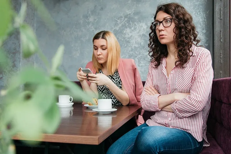 zwei Freundinnen sitzen zusammen ohne Kommunikation beim Treffen