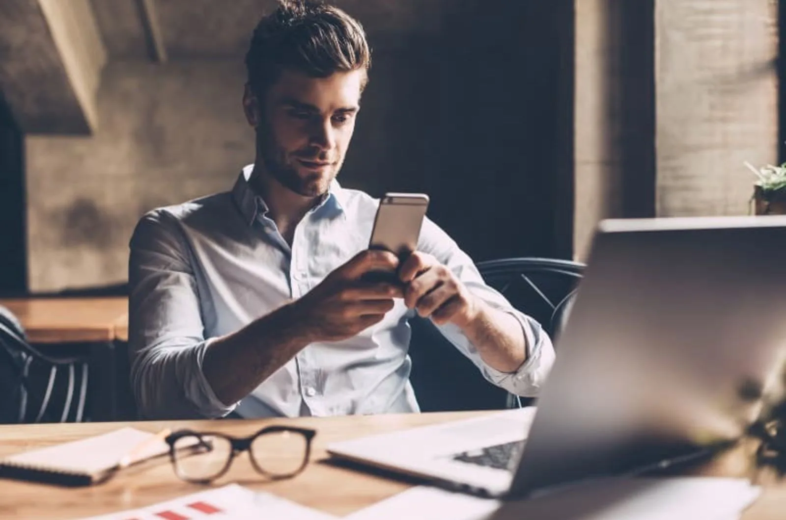 junger Mann tippt am Telefon