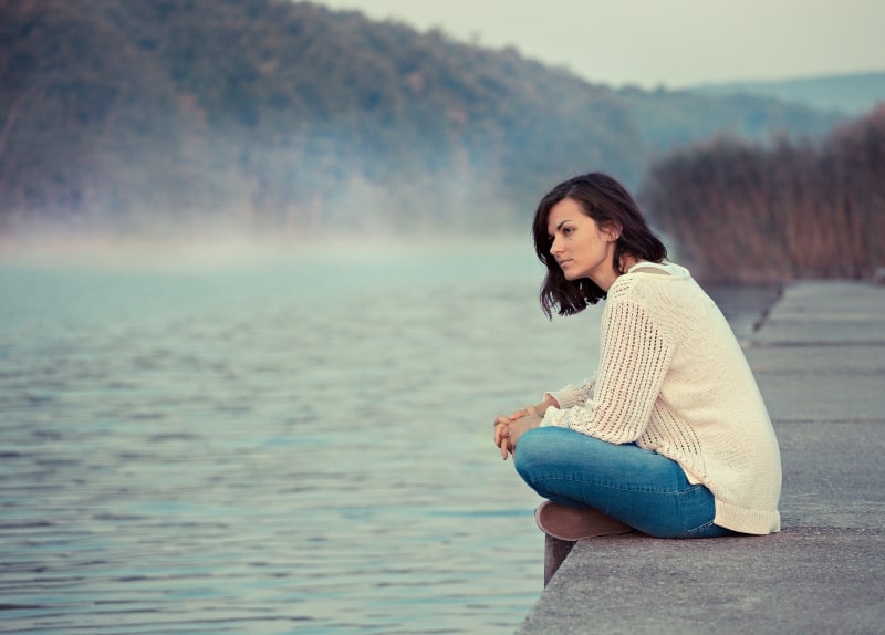 Das Mädchen sitzt in der Nähe des Sees