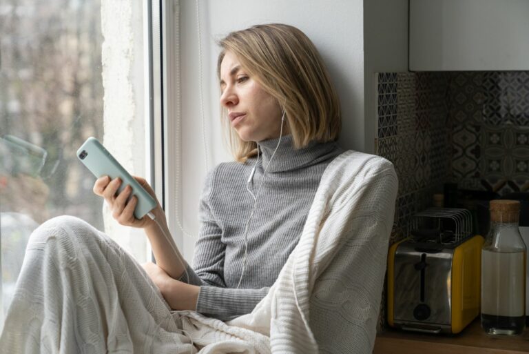 Ein trauriges Mädchen sitzt am Fenster und hört Musik