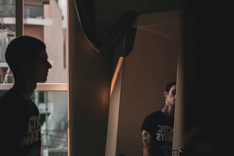 Ein Mann, der sich selbst ansieht, während er vor dem Spiegel im Raum steht