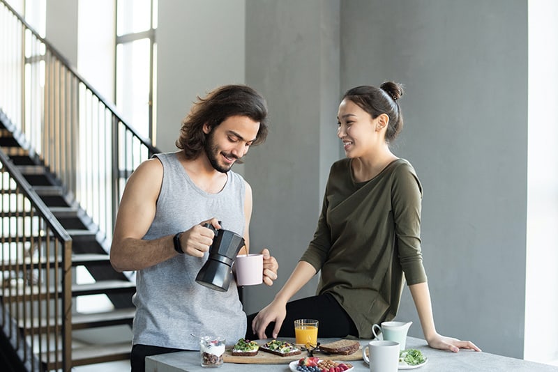 Ein Mann füllt einer Frau während des Frühstücks einen Kaffee in eine Tasse