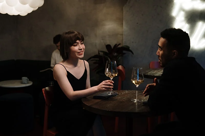 Ein Mann spricht mit einer Frau, während er im Restaurant Wein trinkt