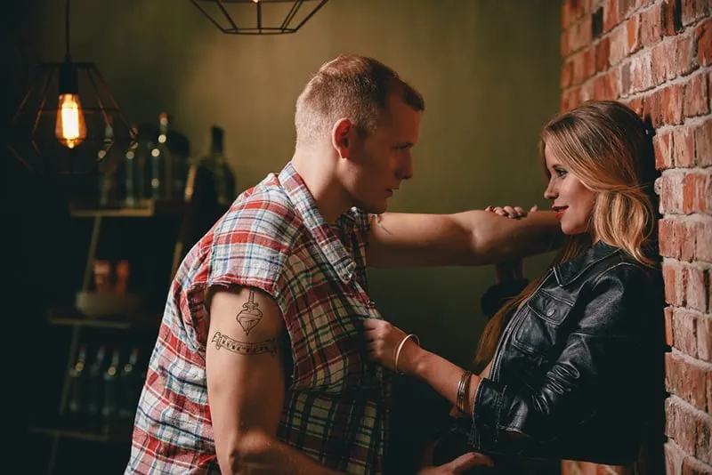 Ein Mann und eine Frau flirten in der Bar, während sie sich an die Wand lehnen