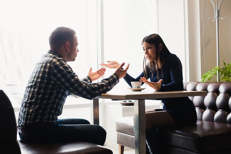 Ein Mann und eine Frau, die sich während eines Gesprächs nicht einig sind, während sie am Tisch sitzen