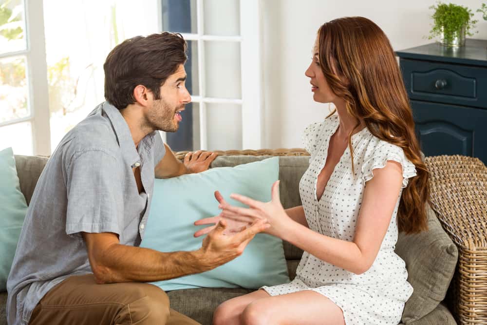 Ein Mann und eine Frau in einem weißen Kleid sitzen auf der Couch und besprechen etwas