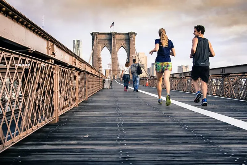 Ein Mann und eine Frau joggen zusammen an der Brücke