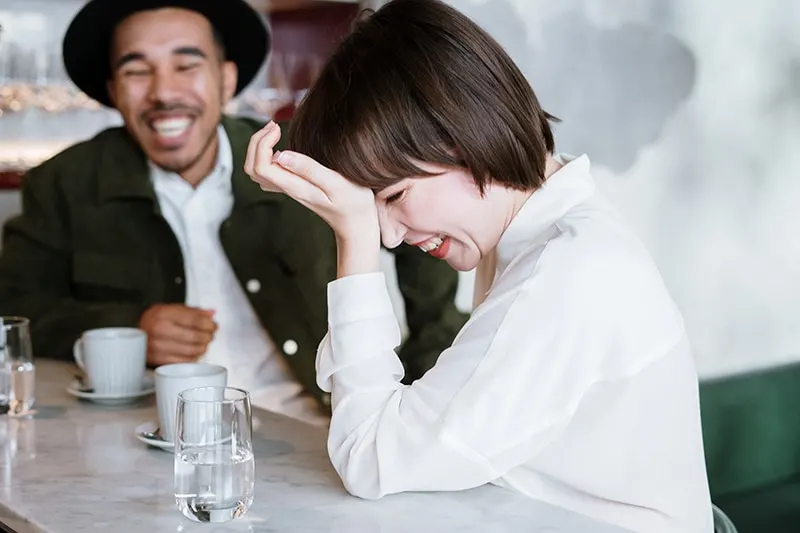 Ein Mann und eine Frau lachen zusammen, während sie im Café sitzen