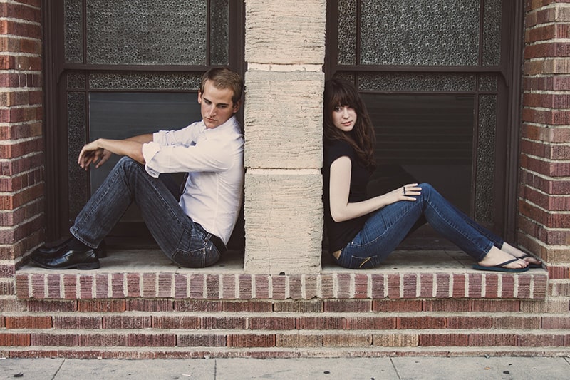 Ein Mann und eine Frau sitzen an der Tür, während beide sich an die Wand zwischen ihnen lehnen