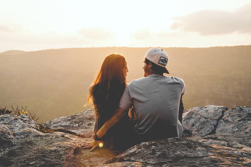 Ein Mann und eine Frau sitzen auf der Klippe und schauen sich an