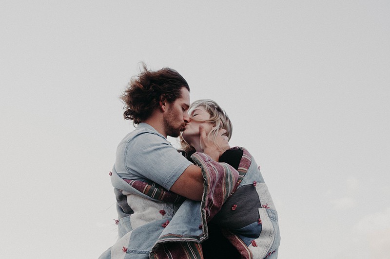 Ein dominanter Mann küsst eine Frau, während er tagsüber draußen steht