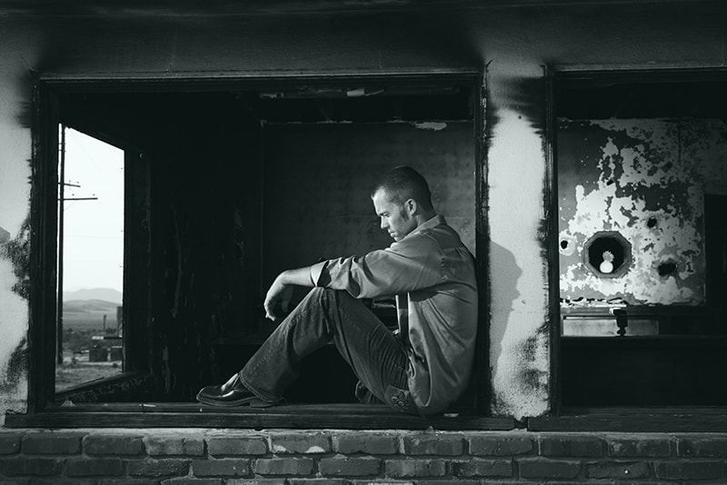Ein trauriger Mann sitzt am Fenster des Gebäudes und schaut nach unten