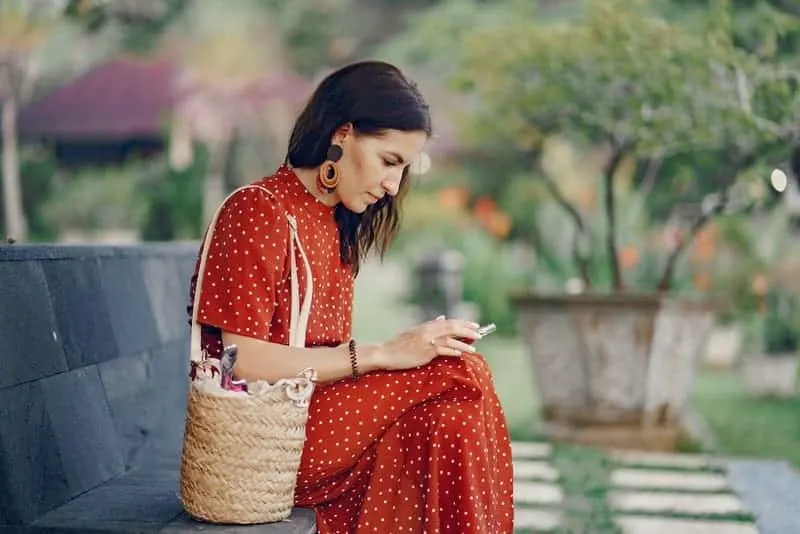 Eine Frau sitzt auf einer Bank und benutzt ein Handy