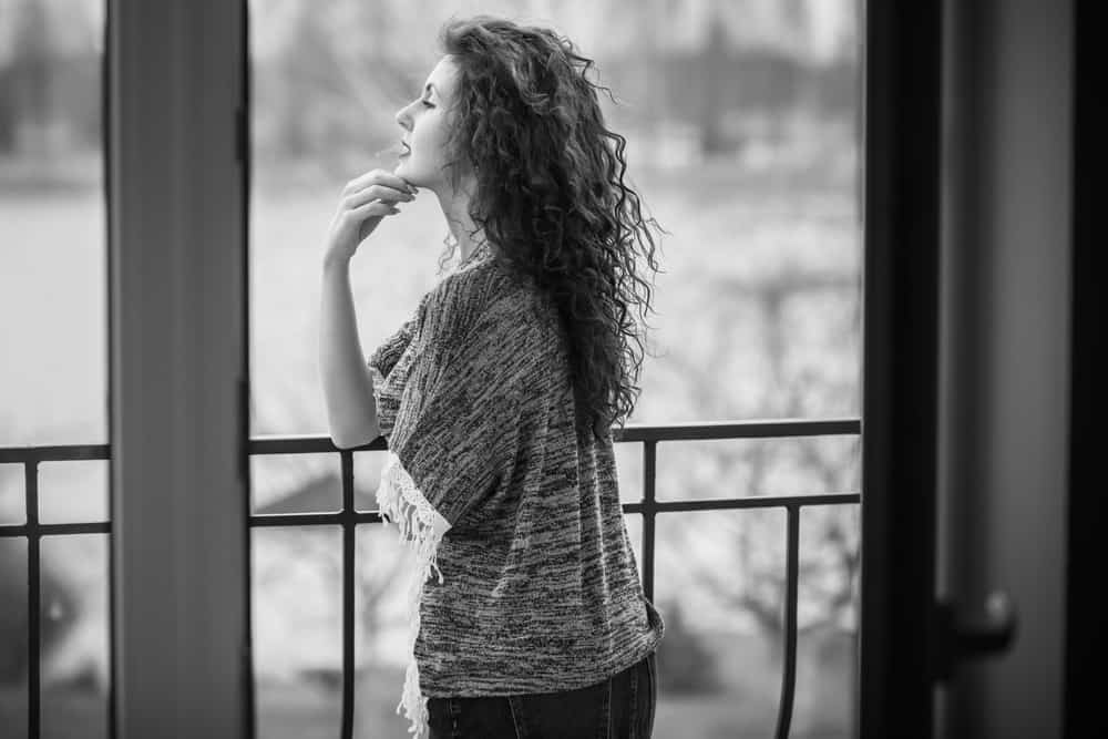 Eine Frau steht auf einem Balkon und lehnt sich an ein Geländer