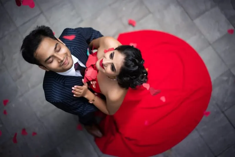 Ein Mann in einem formellen Anzug und eine Frau in einem roten Kleid tanzen auf der Straße