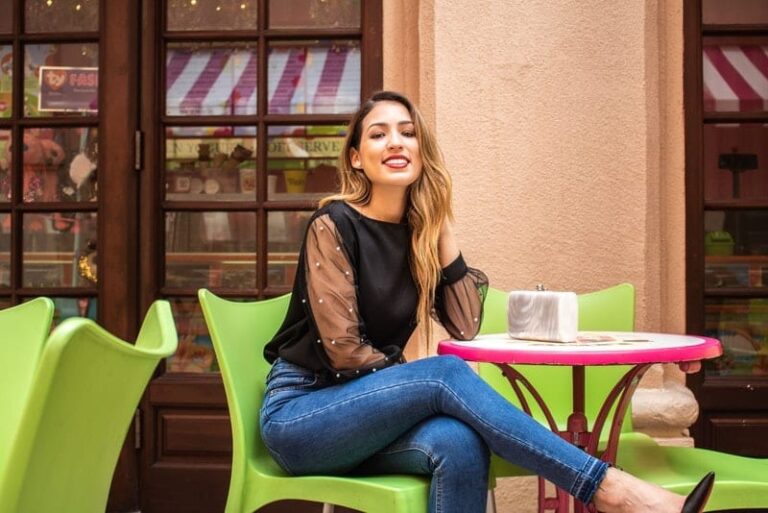 Laechelnde Frau, die am Cafetisch sitzt