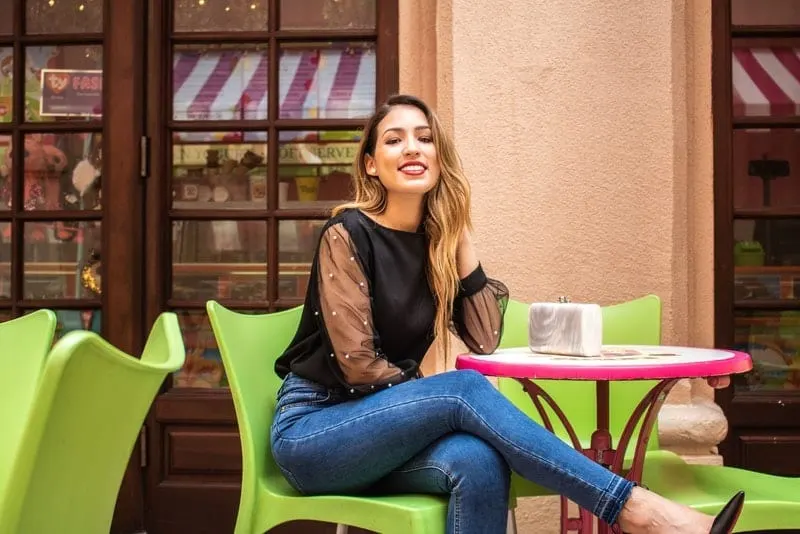 Laechelnde Frau, die am Cafetisch sitzt