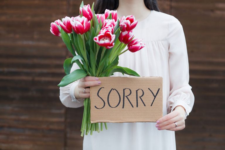Frau, die Blumen und Zeichen des Papiers hält
