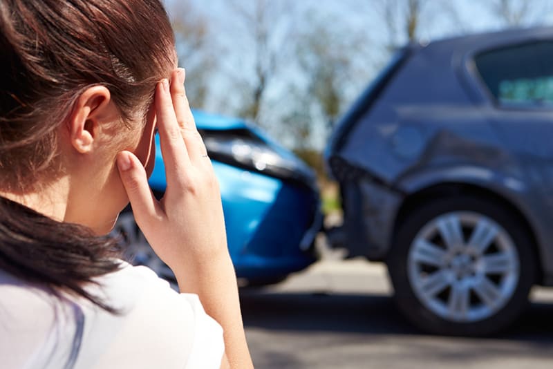 Gestresster Fahrer, der nach Verkehrsunfall am Straßenrand sitzt