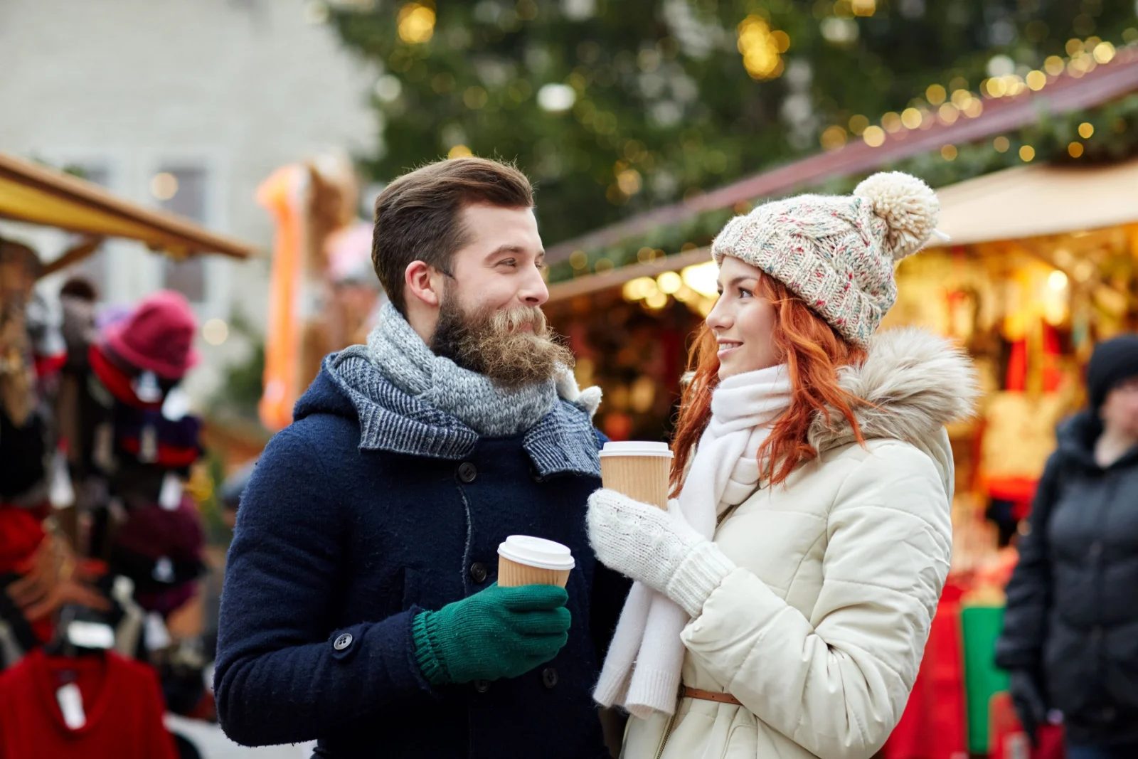 Glückliches Paar in warmer Kleidung, das Kaffee aus Einweg-Pappbechern in der Altstadt trinkt